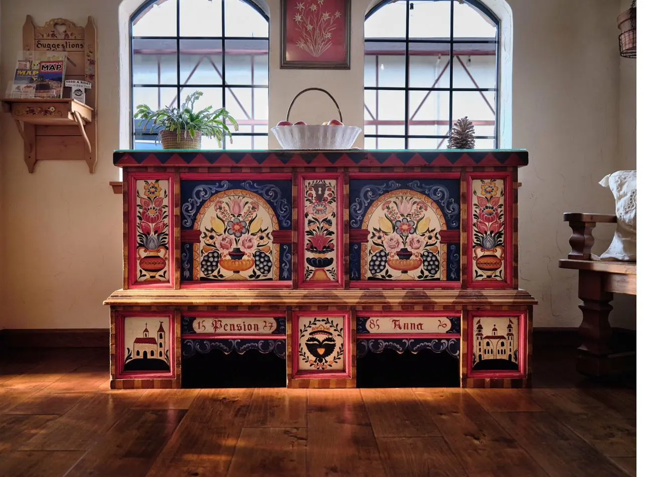 Hand-painted Truhe in Pension Anna lobby — Bauernmalerei with arched floral panels, baroque scrollwork, and Pension Anna inscription