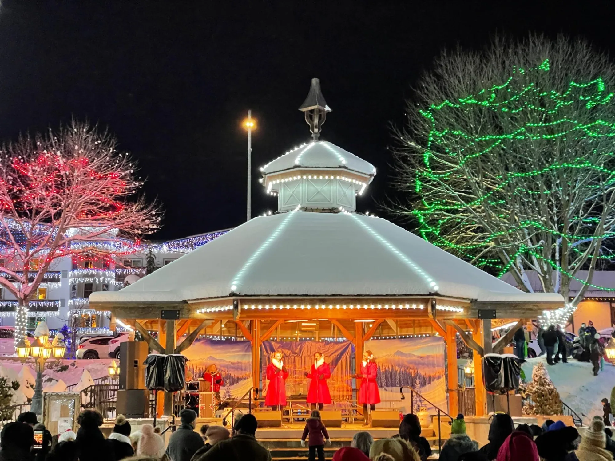 Carolers in red coats performing at the snow-covered Leavenworth gazebo