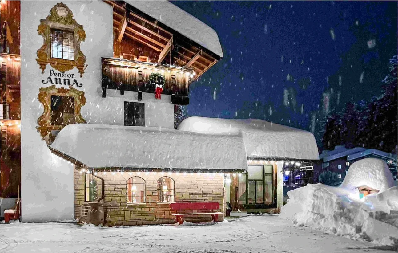 Pension Anna exterior during active Christmas snowstorm at night