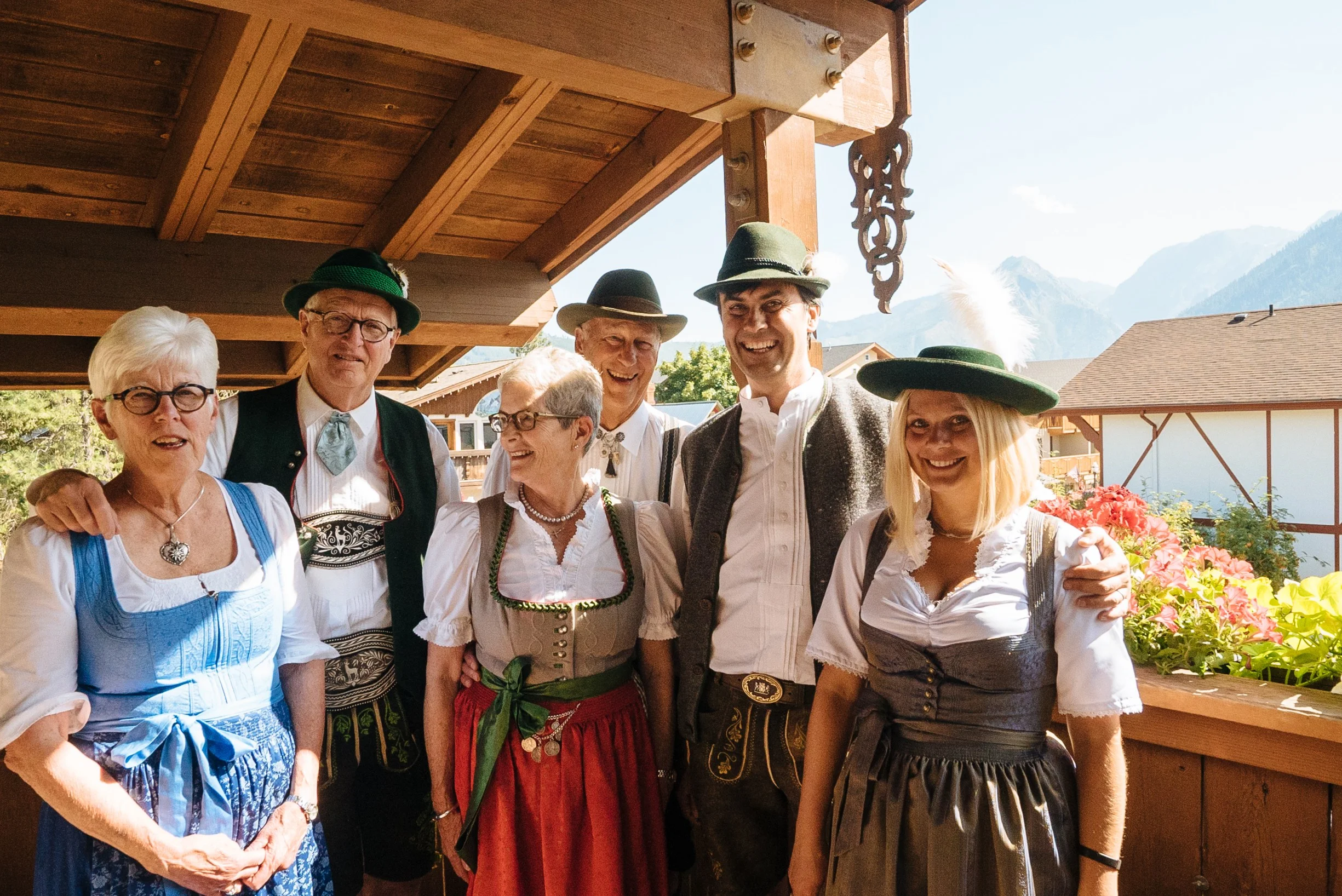 Three generations of Pension Anna owners in traditional Bavarian Tracht — Anne and Bob Smith, Gary and Michelle, and Martin and Erika Szuster — with the Cascade Mountains behind them