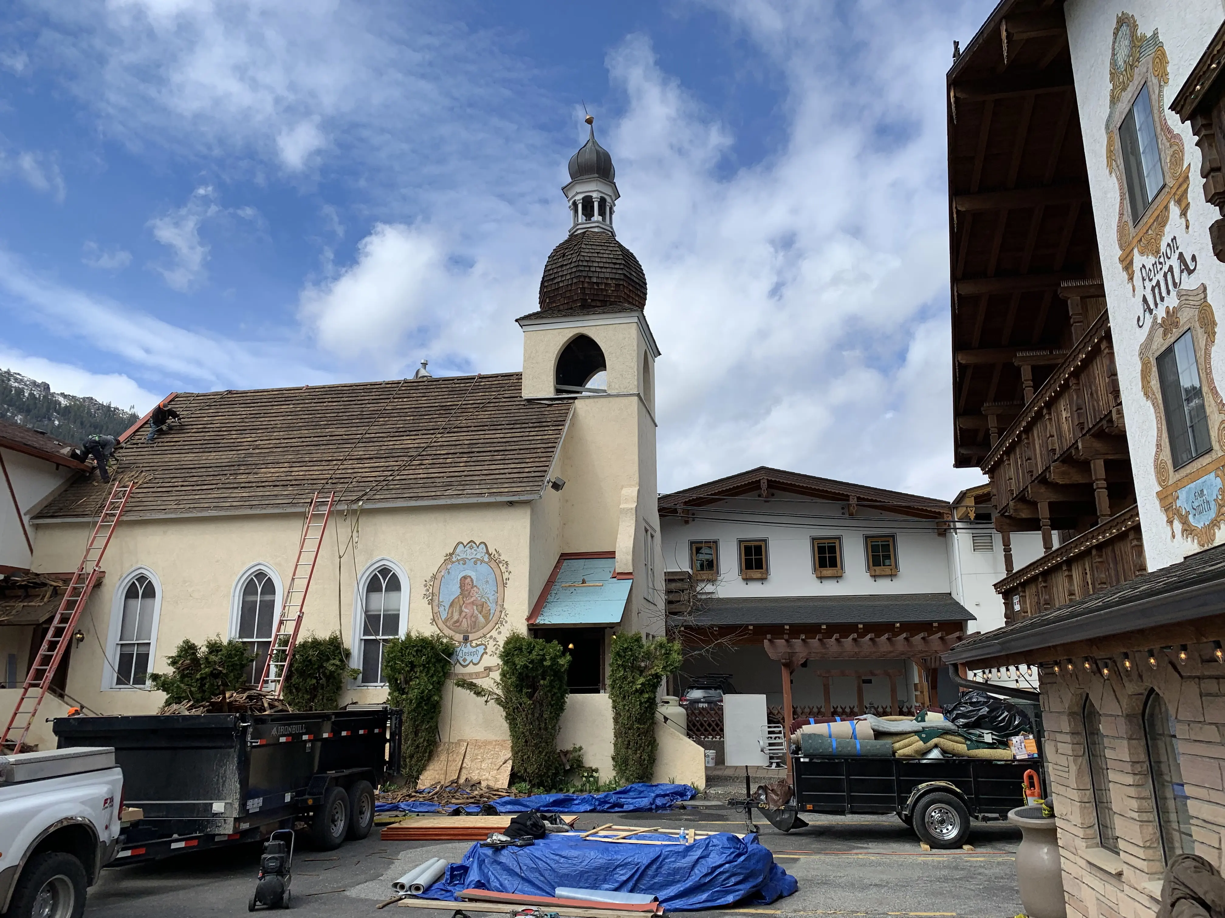 Roofers working on the Alte Kapelle chapel during the 2019 roof replacement, Pension Anna facade visible