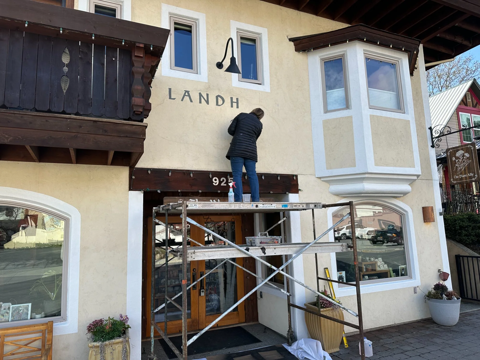 Erika Szuster on scaffolding applying the Landhaus Erika lettering to the building facade, Leavenworth 2025