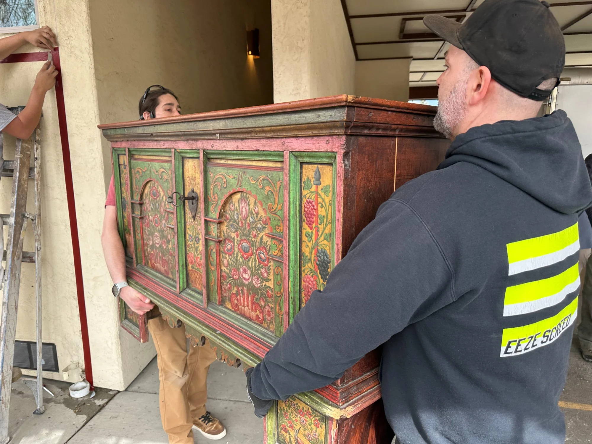 A hand-painted Tirolean antique chest being carried into Landhaus Erika during the 2025 opening