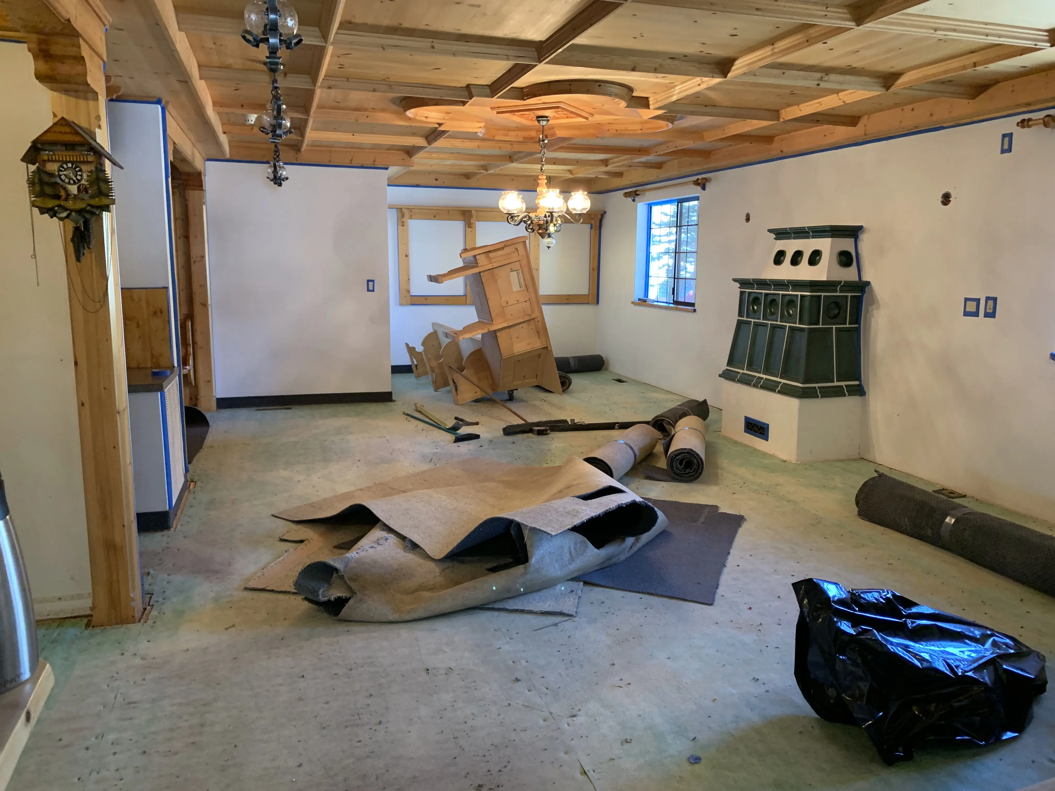 Pension Anna breakfast room stripped to subfloor during the 2019 remodel, kachelofen and timber ceiling visible