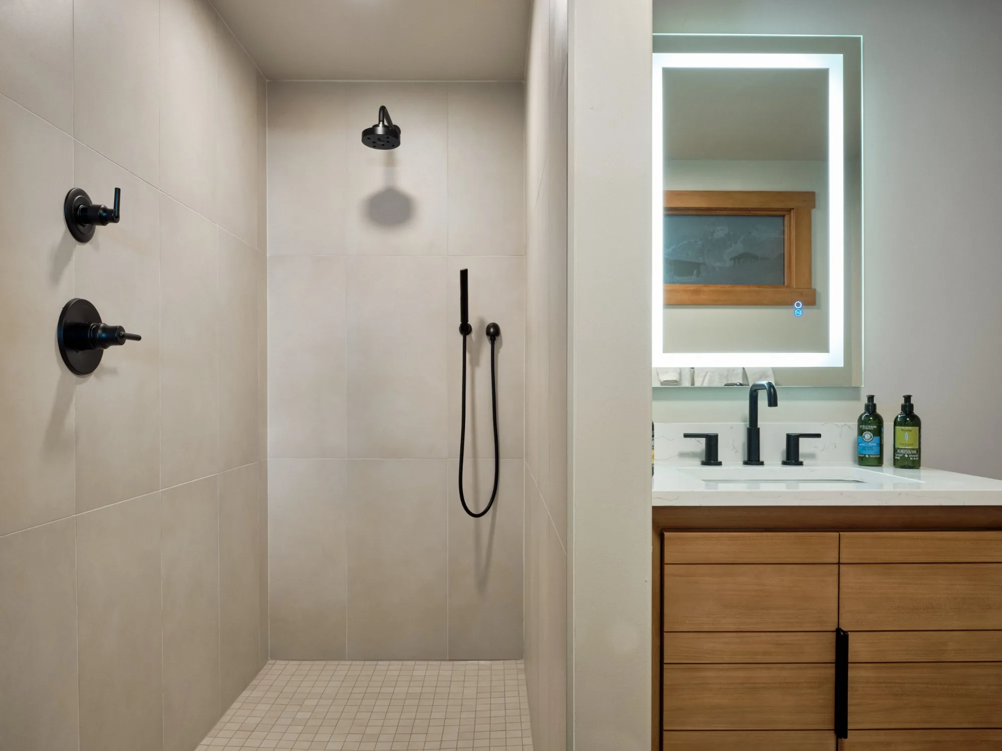 Solstice Suite walk-in shower with matte black fixtures and lit vanity mirror