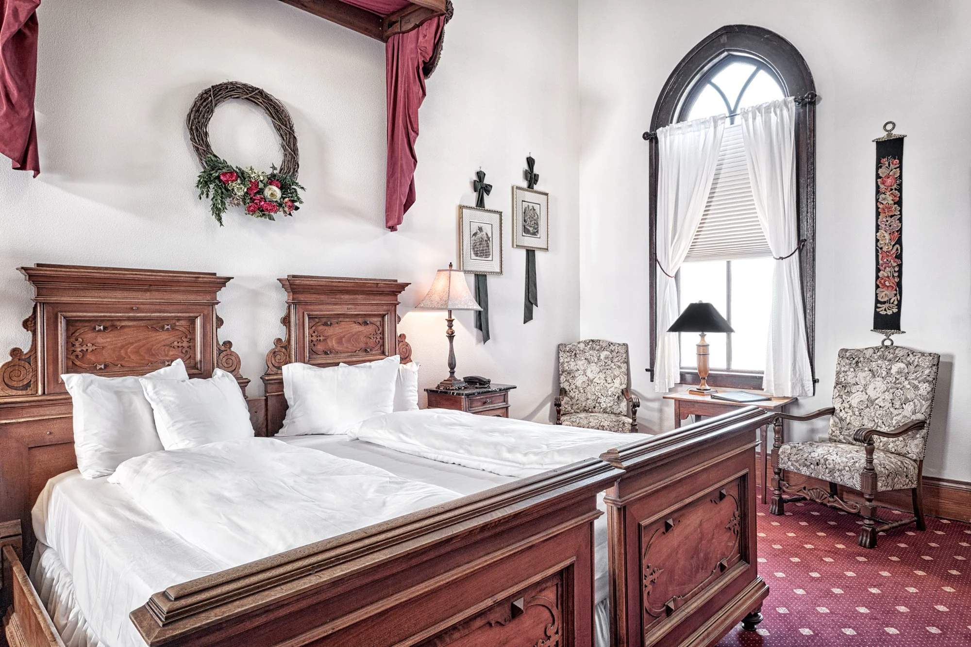 Pfaffenwinkl bedroom with antique walnut bed, Gothic arched window, and tapestry armchairs
