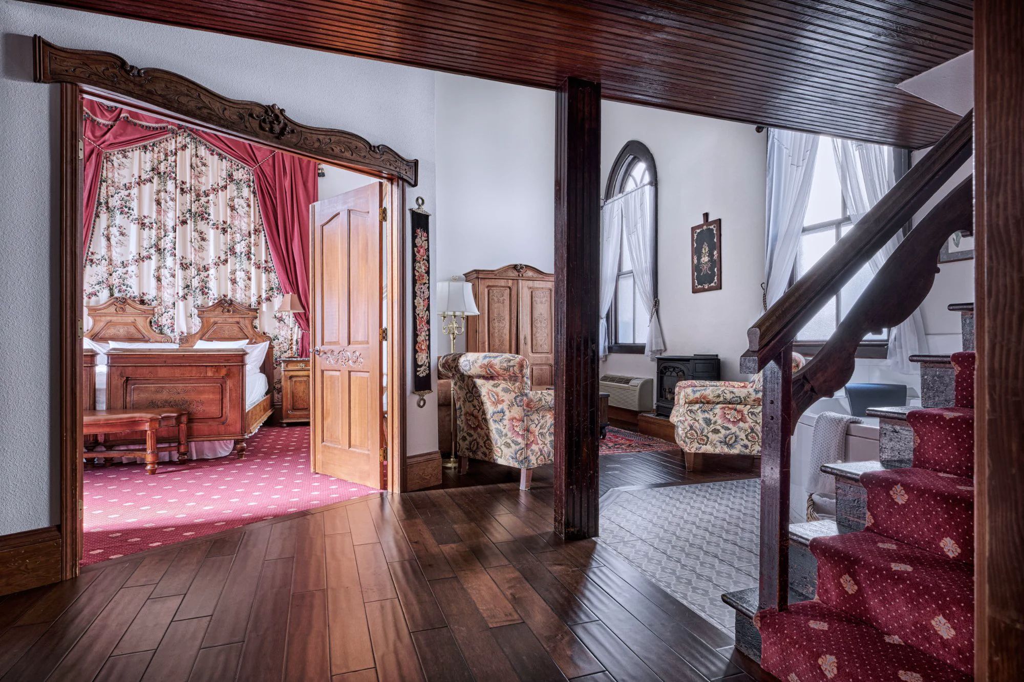 Alte Kapelle Suite entry through ornate carved doorframe into bedroom and living area