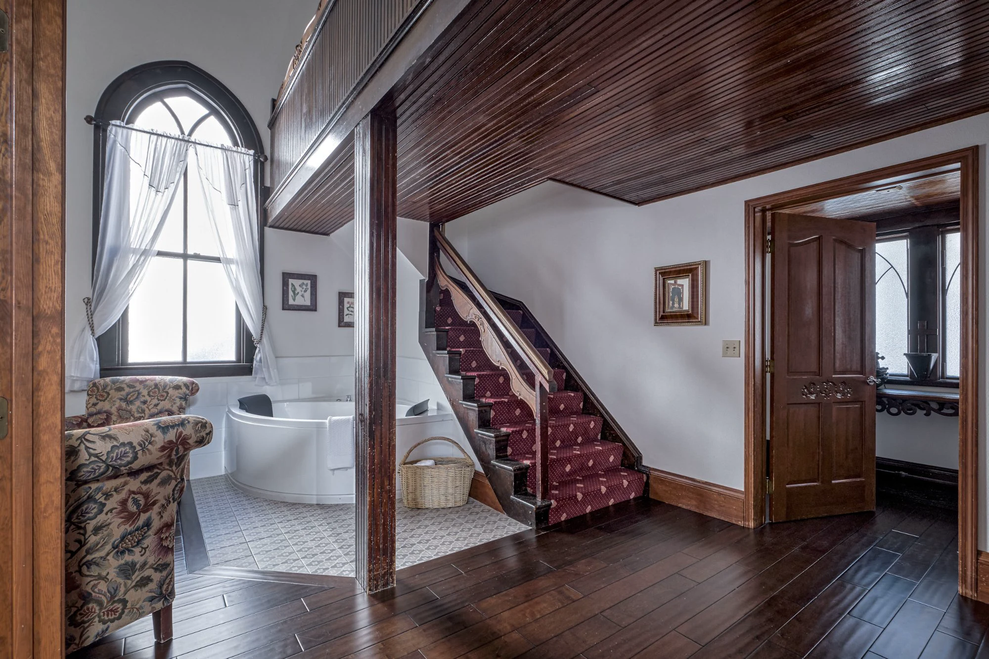 Alte Kapelle Suite Jacuzzi tub at base of carved staircase with Gothic arched window